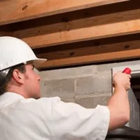Termite inspection technician checking a basement wall and framing for termite activity in Pasadena, CA